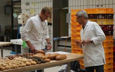 Das Bild zeigt einen jungen Bäcker umgeben von frisch zubereiteten Backutensilien