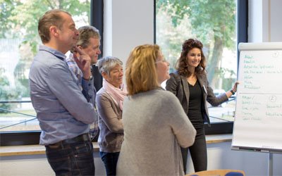 Das Bild zeigt Teilnehmer in einem Seminar vor einem Flipchart